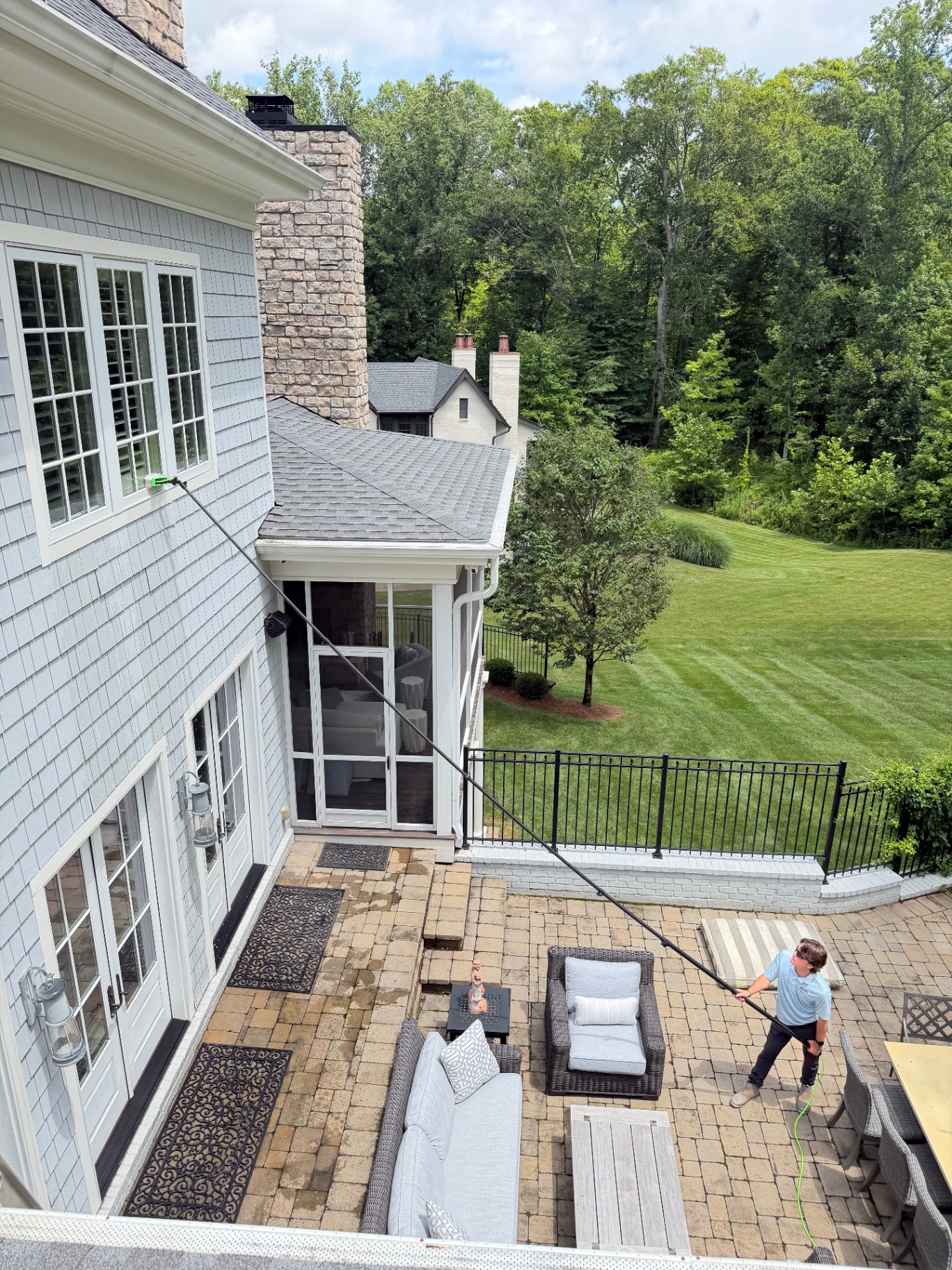 Swabby crew member cleaning large exterior windows on a beautiful Louisville home